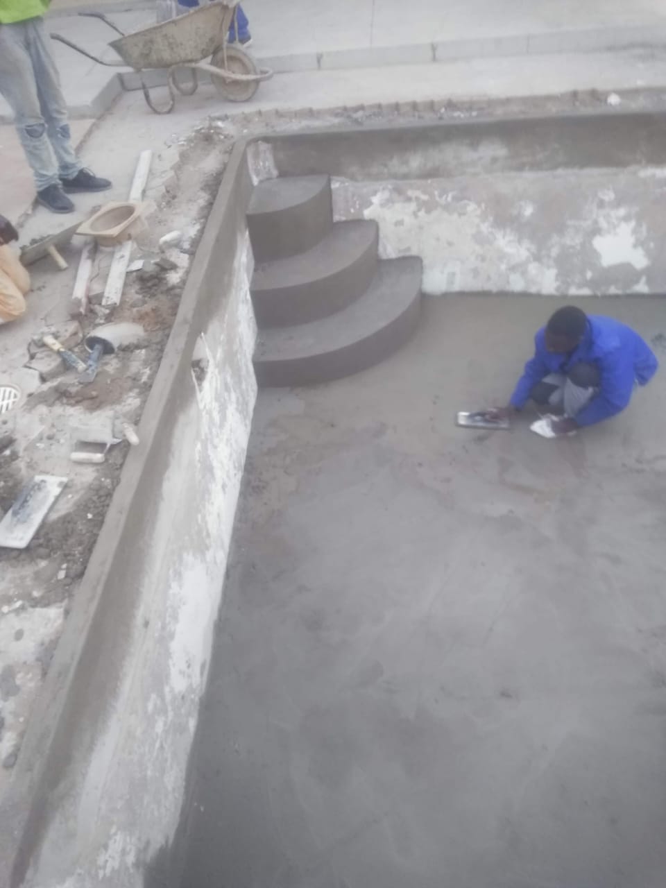 Technicians plastering the floor and steps of a pool under construction