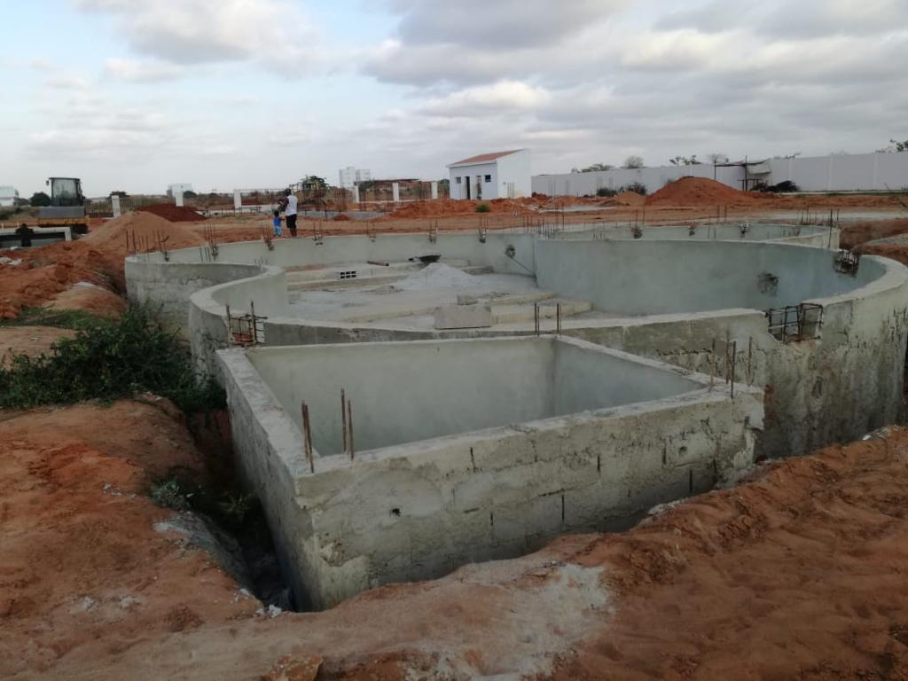 Concrete pool shell under construction on a cleared site