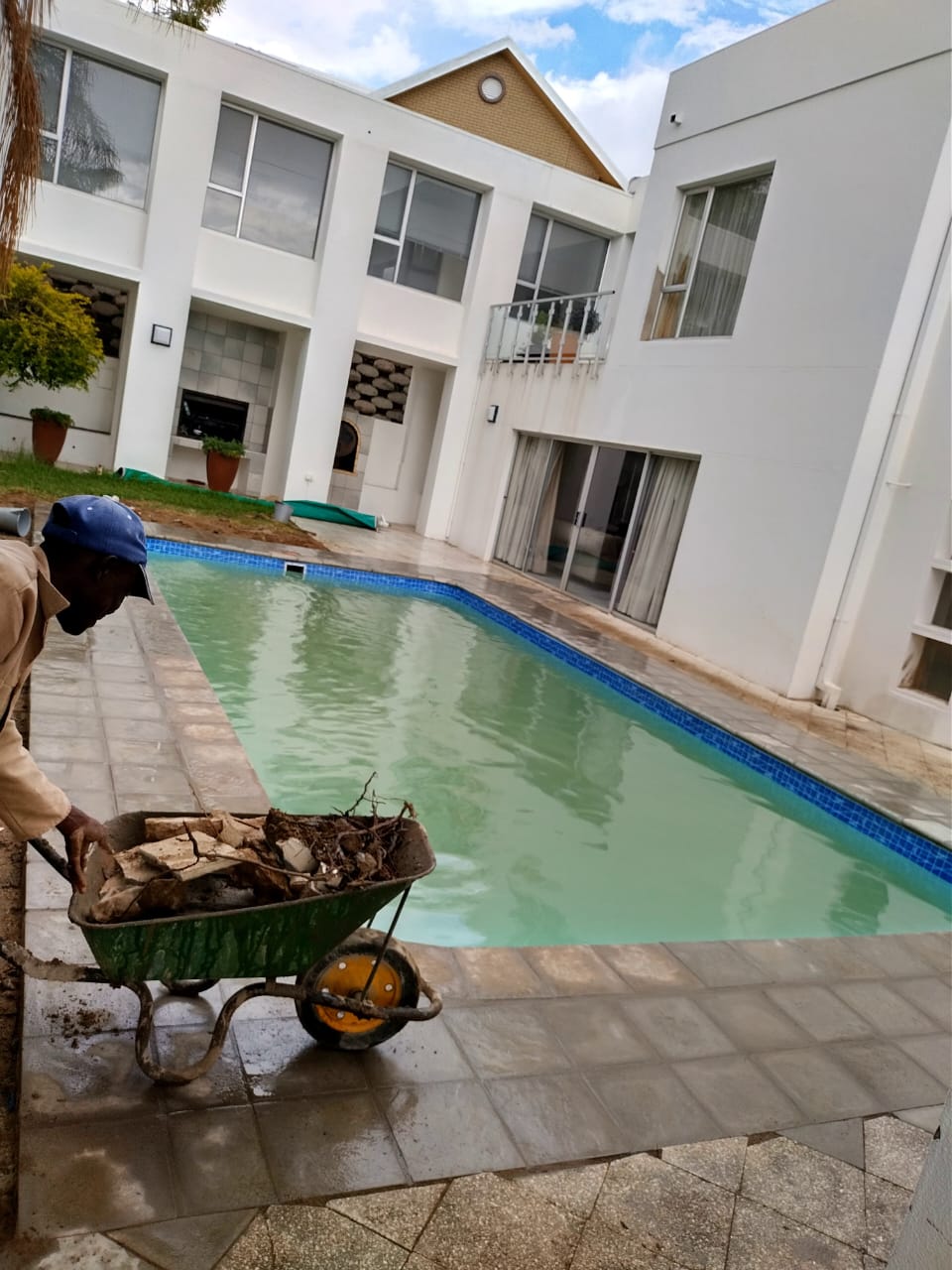Technician removing debris from a poolside in a wheelbarrow