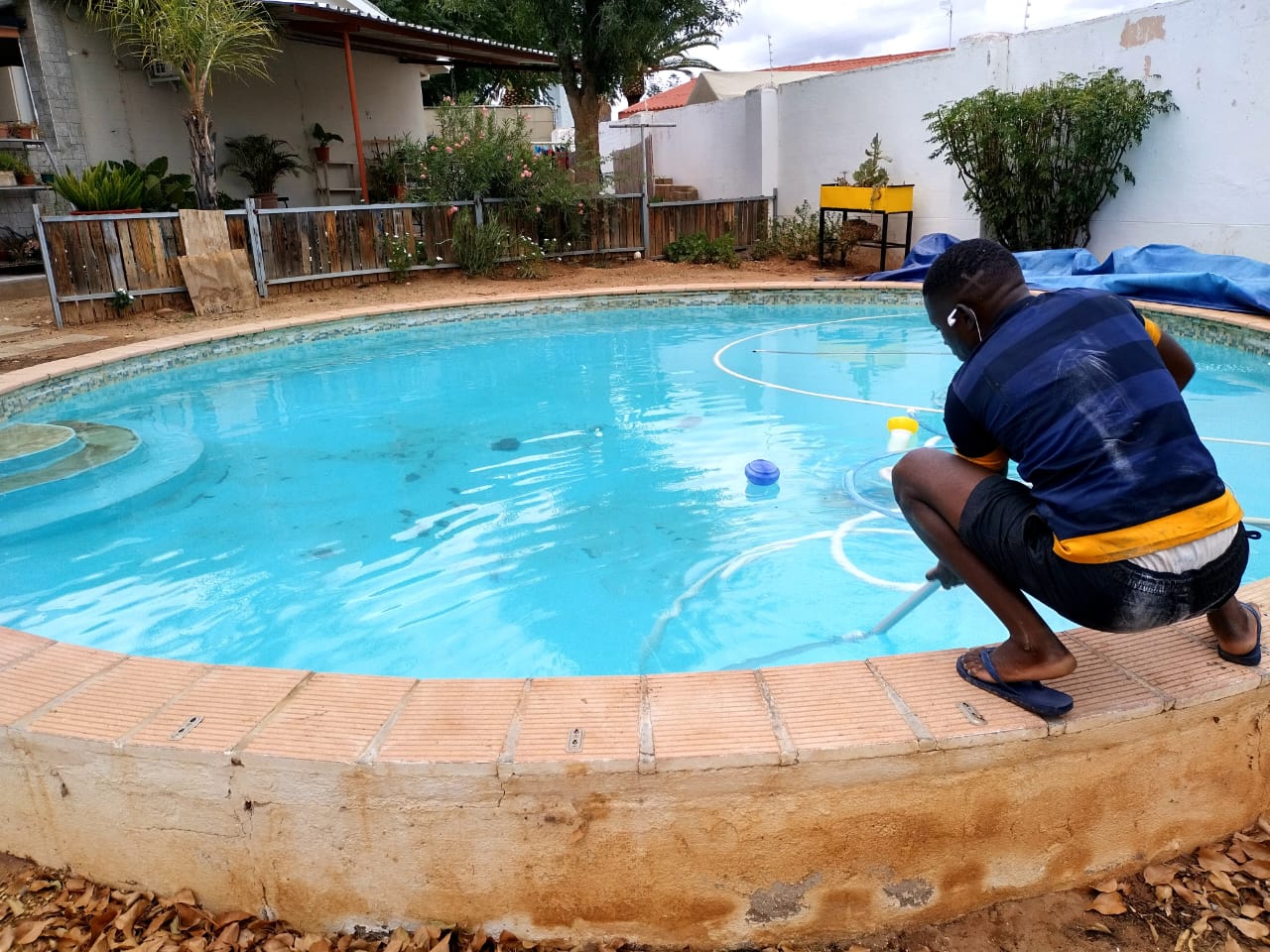 Perfect Pools technician brushing and vacuuming a residential pool