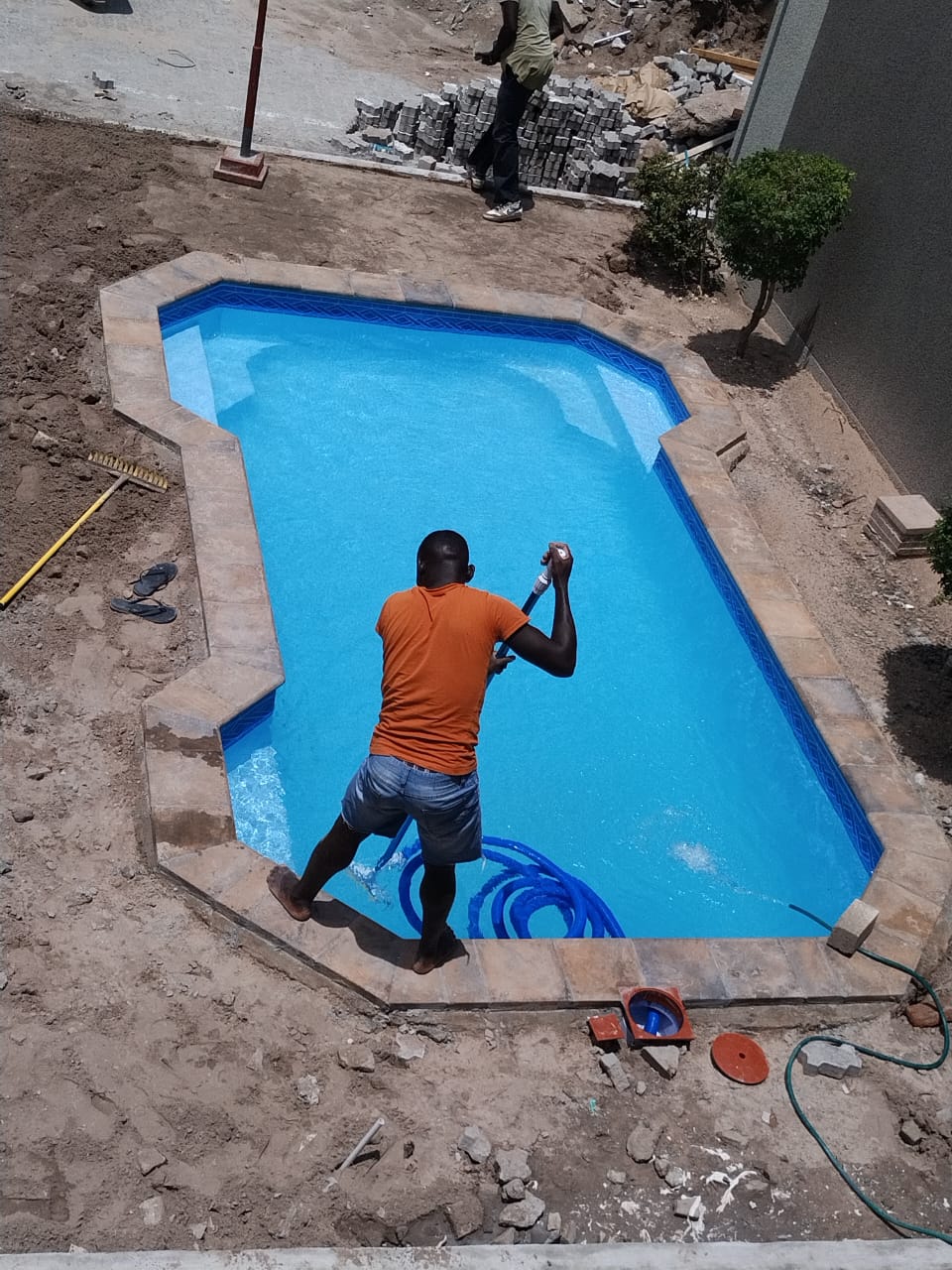 Technician filling a freshly finished blue pool