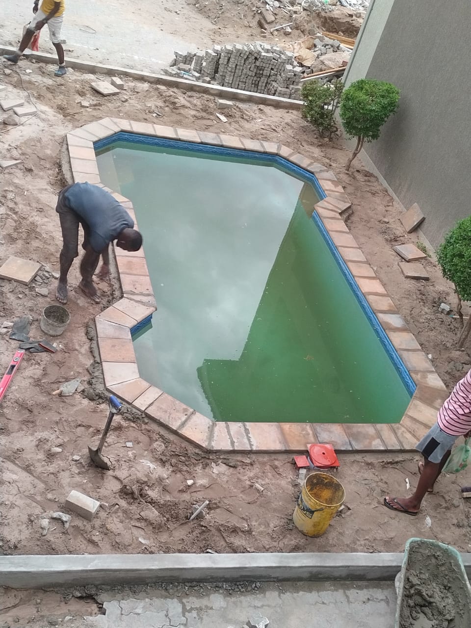 Worker laying coping tiles around a newly built pool