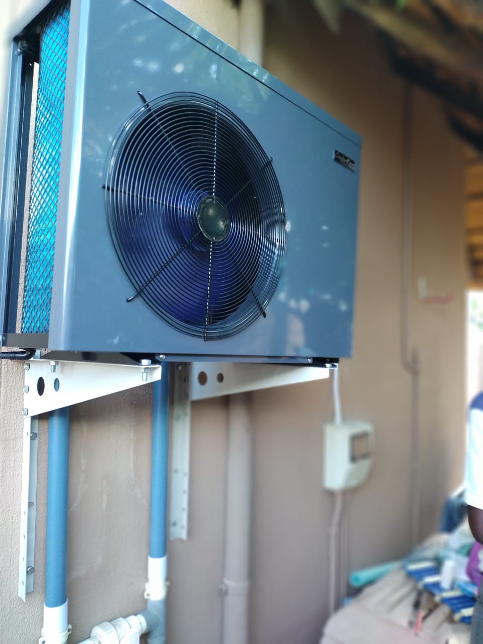 Wall-mounted pool heat pump installed with new pipework