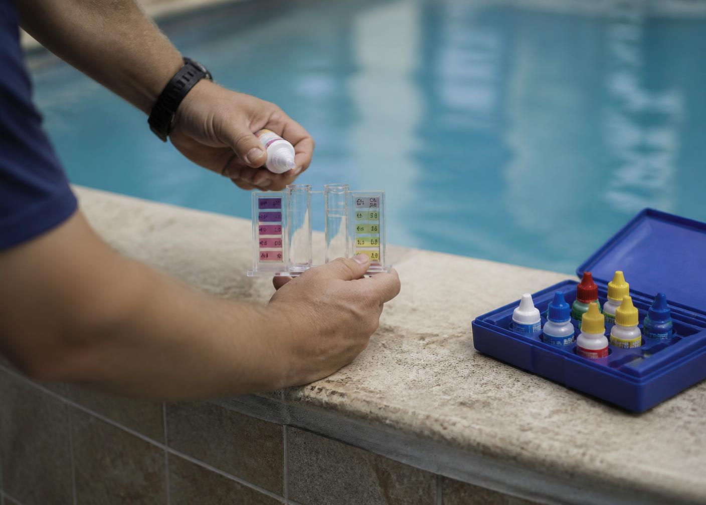 Pool technician testing chlorine and pH levels at the edge of a clean pool